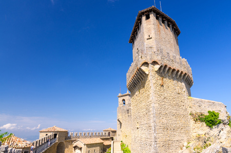 Prima Torre Guaita first medieval tower with stone brick fortress wall with merlons on Mount Titano rock, blue sky white clouds copy space background, Republic San Marinoのeditorial素材