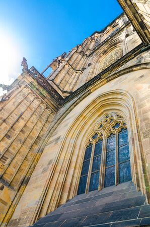 View from below of window of South Tower - exterior of St. Vitus Cathedral in Prague Castle Hradcany Lesser Town Mala Strana district, blue sky background, Bohemia, Czech Republicの写真素材