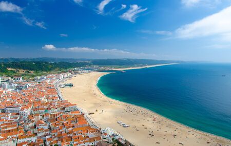 Portugal, panoramic view of Nazare in summer, mountain landscape with dense greenery in the background, Nazare coastline with white sand and blue azure water of the Atlantic Ocean, harbor Nazareの写真素材