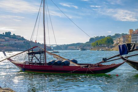 Portugal, Porto in summer, panoramic view of  Douro river, red wooden boat with wine port barrels close-up, the banks of the river Douroの写真素材