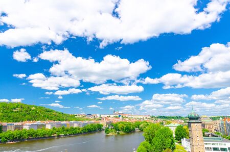 Aerial panoramic view of Prague city, historical center with Prague Castle, St. Vitus Cathedral, Hradcany district, green hills, Vltava river, blue sky white clouds background, Bohemia, Czech Republicの写真素材