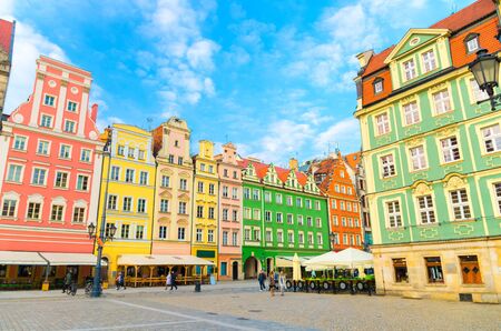 Row of colorful traditional buildings with multicolored facades and street lamp on cobblestone Rynek Market Square in old town historical city centre of Wroclaw, blue sky background, Polandの写真素材