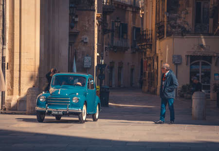 Lecce, Italy - April 23, 2017: Vintage retro small blue car Fiat with man driver inside ride to the central square Piazza del Duomo for exhibition, Puglia Apulia region, Southern Italyのeditorial素材