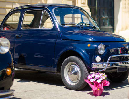 Lecce, Italy - April 23, 2016: Front left side view of vintage classic retro blue automobile car with bunch of flowers parked in a street of Lecce city, Puglia Apulia region, Southern Italyのeditorial素材