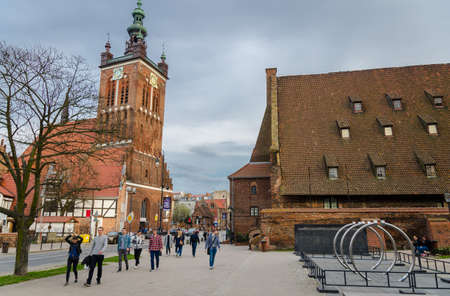 Gdansk, Poland, April 15, 2018: St. Catherine's parish Protestant Roman Catholic Church with tower clock and large water mill Wielki Mlyn with tile roof near Radunia Canal in historic old townのeditorial素材
