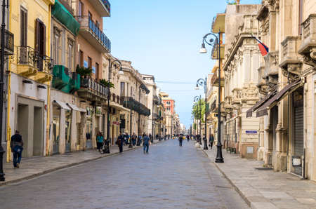 Italy, Reggio di Calabria, May 11, 2018: Pedestrian tourist street Corso Giuseppe Garibaldi with old traditional typical buildings, lamps and green trees in historical centre of the cityのeditorial素材