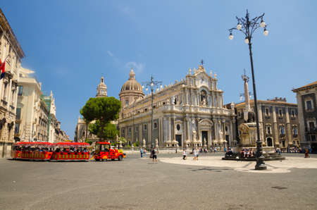 Italy, Catania, May 13, 2018: Elephant Statue fountain, Cathedral of Santa Agatha, touristic red train and walking people on Piazza del Duomo square in Catania city centre, Sicilyのeditorial素材