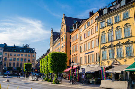 Sweden, Stockholm, May 29, 2018: Traditional typical buildings with colorful walls, green trees on Kornhamnstorg harbour square in old historical town quarter Gamla Stan of Stadsholmen islandのeditorial素材