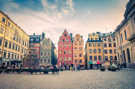 Sweden, Stockholm, May 29, 2018: traditional typical buildings with colorful walls, Nobel Museum and fountain on Stortorget square in old town quarter Gamla Stan of Stadsholmen island, blue sky aboveのeditorial素材