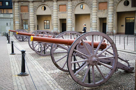 Sweden, Stockholm, May 29, 2018: Guard soldier at post near row old cannons in courtyard square of Swedish Royal Palace official residence of King of Sweden in old historical town quarter Gamla Stanのeditorial素材
