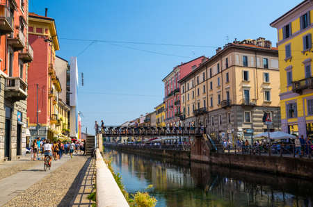 Milan, Italy, September 9, 2018: Bridge Pont de fer across water of Naviglio Grande grand canal waterway, embankment, promenade and colourful buildings in beautiful summer day with blue sky, Lombardyのeditorial素材