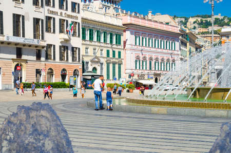 Genoa, Italy, September 11, 2018: father man and son boy are playing walking down the Piazza Raffaele de Ferrari square near fountain in old historical city Genova centre in beautiful summer dayのeditorial素材