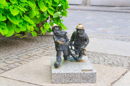 Wroclaw, Poland, May 7, 2019: two Dwarf firemen firefighters is running with ladder and tap, famous bronze miniature gnome with hat sculpture is a symbol of Wroclaw in old historical city centreのeditorial素材
