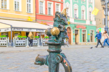 Wroclaw, Poland, May 7, 2019: Dwarf is sitting on street water tap on Rynek Market Square, famous bronze miniature gnome with hat sculpture is a symbol of Wroclaw in old historical city centreのeditorial素材