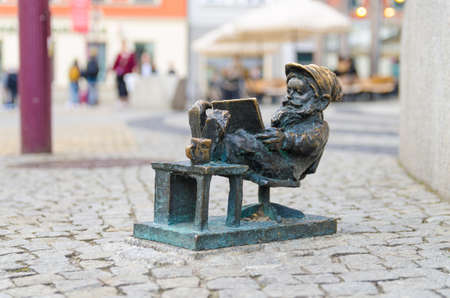 Wroclaw, Poland, May 7, 2019: Dwarf is sitting and reading a book, famous bronze miniature gnome with hat sculpture is a symbol of Wroclaw in old historical city centreのeditorial素材