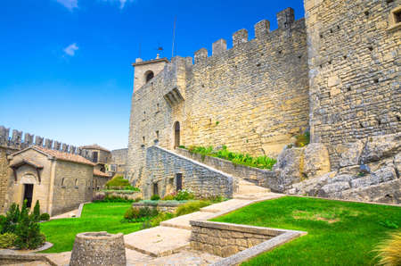 Republic San Marino, September 18, 2018: Courtyard with green grass lawn of Prima Torre Guaita first medieval tower with stone brick fortress wall with merlons on Mount Titano rock with blue skyのeditorial素材