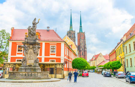 Wroclaw, Poland, May 7, 2019: Monument on square and cobblestone road street with green trees to Cathedral of St. John the Baptist building with two spires in old historical city centre, Ostrow Tumskiのeditorial素材