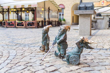 Wroclaw, Poland, May 7, 2019: three Dwarfs: deaf, blind with a stick and invalid in a wheelchair, famous bronze miniature gnome with hat sculpture is a symbol of Wroclaw in old historical city centreのeditorial素材