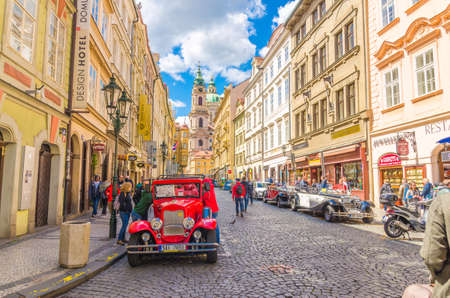 Prague, Czech Republic, May 13, 2019: old retro vintage car on cobblestone street in Lesser Town, buildings with old colorful facades, Church of Saint Nicholas is Baroque catholic church backgroundのeditorial素材