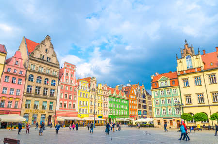 Wroclaw, Poland, May 7, 2019: Row of colorful traditional buildings with multicolored facades and walking people on cobblestone Rynek Market Square in old town historical city centreのeditorial素材