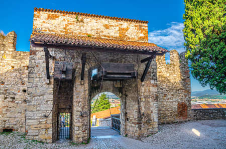 Brescia, Italy, September 11, 2019: Stone wall with merlons and drawbridge Gate of medieval Castle of Brescia or Castello di Brescia or Falcon of Italy, historical city centre, Lombardyのeditorial素材