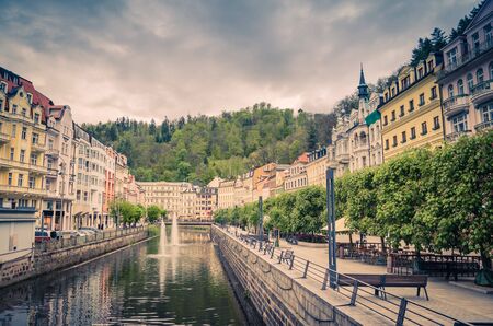 Karlovy Vary Carlsbad historical city centre, central embankment of Tepla river with fountains, colorful beautiful buildings, Slavkov Forest hills green trees background, West Bohemia, Czech Republicの写真素材