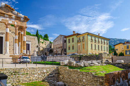 Brescia, Italy, September 11, 2019: Capitolium of Brixia or Temple of Capitoline Triad or Tempio Capitolino ruins and Palazzo Maggi Gambara palace, historical centre, blue sky and hills, Lombardyのeditorial素材