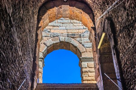 Blue clear sky through limestone brick arch window of The Verona Arena, staircase and corridor foreground, Roman amphitheatre ancient building, Verona city historical centre, Veneto Region, Italyの写真素材