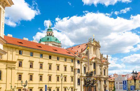 The Church of Saint Nicholas is Baroque catholic church in the Lesser Town, Column of the Holy Trinity on square in Mala Strana district, blue sky white clouds background, Bohemia, Czech Republicの写真素材