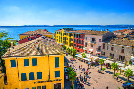 Sirmione, Italy, September 11, 2019: aerial panoramic view of historical centre pedestrian street Castle square piazza Castello, multicolored colorful buildings with red tiled roofs and Garda lakeのeditorial素材