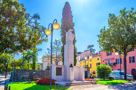 Desenzano del Garda, Italy, September 11, 2019: Achille Papa eagle monument and cannon on green grass lawn in historical town centre, blue sky background, Lombardyのeditorial素材