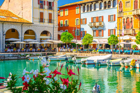 Desenzano del Garda, Italy, September 11, 2019: Old harbour Porto Vecchio with boats on turquoise water, street restaurants and traditional buildings in historical town centre, Lombardyのeditorial素材
