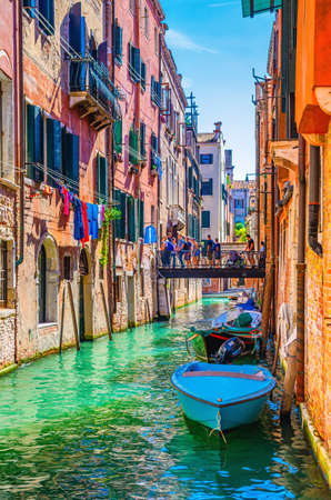 Venice, Italy, September 13, 2019: cityscape with narrow water canal with boats moored between old colorful buildings, Veneto Region. Typical Venetian view, vertical view, blue sky backgroundのeditorial素材