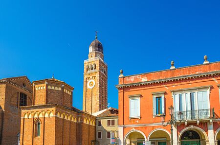 Clock and bell tower of Cathedral Santa Maria Assunta Duomo Roman catholic church building in Chioggia town historical centre, blue sky background in summer day, Veneto Region, Northern Italyの写真素材