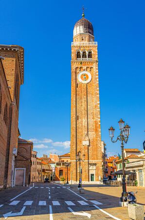 Clock and bell tower of Cathedral Santa Maria Assunta Duomo Roman catholic church building in Chioggia town historical centre, blue sky background in summer day, Veneto Region, Northern Italyの写真素材