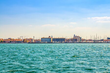 Panoramic view from sea lagoon of Chioggia town cityscape with port and old buildings in historical centre, blue sky background in summer day, Veneto Region, Northern Italyの写真素材