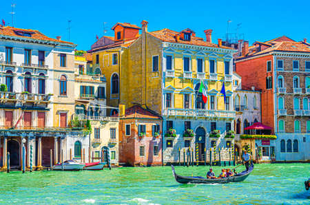 Venice, Italy, September 13, 2019: gondolier and tourists on gondola traditional boat sailing on water of Grand Canal waterway with Venetian architecture typical colorful buildings backgroundのeditorial素材