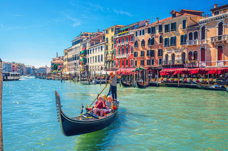 Venice, Italy, September 13, 2019: gondolier and tourists on gondola traditional boat sailing on water of Grand Canal waterway with Venetian architecture typical colorful buildings backgroundのeditorial素材