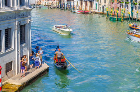 Venice, Italy, September 13, 2019: gondolier and tourists on gondola traditional boat sailing on water of Grand Canal waterway with Venetian architecture typical buildings backgroundのeditorial素材