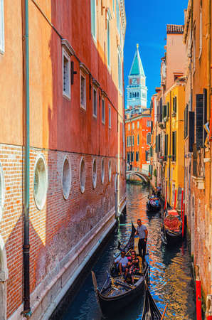 Venice, Italy, September 13, 2019: gondolier on gondola traditional boat with tourists people sailing in narrow water canal between old colorful buildings in historical city centre, Veneto Regionのeditorial素材