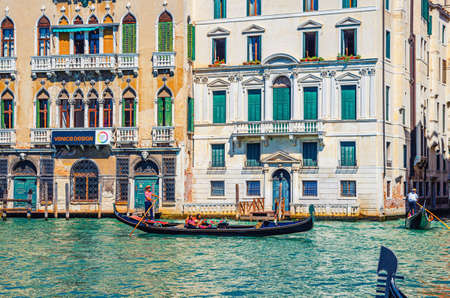 Venice, Italy, September 13, 2019: gondolier and tourists on gondola traditional boat sailing on water of Grand Canal waterway with Venetian architecture typical colorful buildings backgroundのeditorial素材