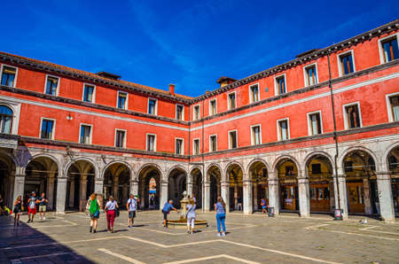 Venice, Italy, September 13, 2019: people tourists walking down Campo San Giacomo di Rialto square with Sezioni Civili Tribunale building in historical city centre, blue sky background, Veneto Regionのeditorial素材