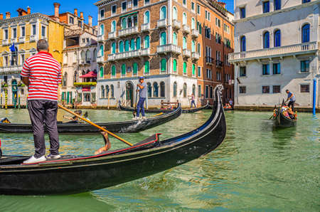 Venice, Italy, September 13, 2019: gondolier and tourists on gondola traditional boat sailing on water of Grand Canal waterway with Venetian architecture typical colorful buildings backgroundのeditorial素材
