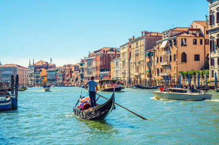Venice, Italy, September 13, 2019: gondolier and tourists on gondola traditional boat sailing on water of Grand Canal waterway with Venetian architecture typical colorful buildings backgroundのeditorial素材