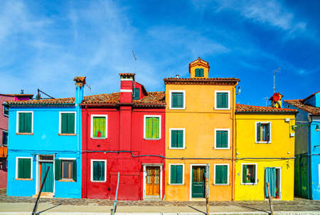 Row of colorful houses in Burano island. Multicolored buildings on fondamenta embankment of water canal, blue sky in sunny day, Venice Province, Veneto Region, Northern Italy. Burano postcardの写真素材