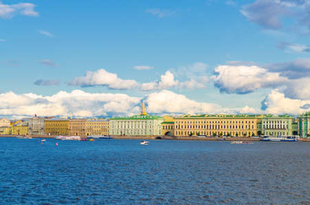 Cityscape of Saint Petersburg Leningrad city with row of old colorful buildings on embankment in historical city center and boat ship on water of Neva river, blue cloudy sky background, Russiaの写真素材