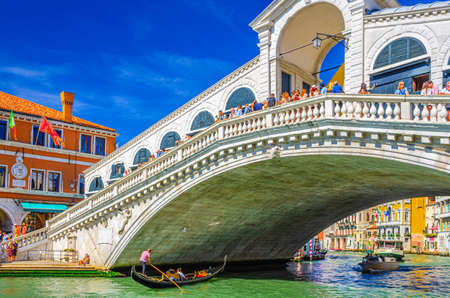 Venice, Italy, September 13, 2019: cityscape with Rialto Bridge across Grand Canal waterway, Venetian architecture colorful buildings, gondolas boats sailing Canal Grande, blue sky in sunny dayのeditorial素材
