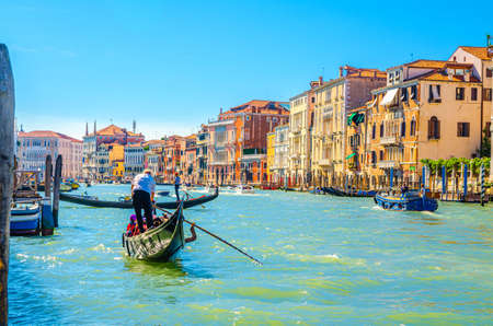 Venice, Italy, September 13, 2019: gondolier and tourists on gondola traditional boat sailing on water of Grand Canal waterway with Venetian architecture typical colorful buildings backgroundのeditorial素材