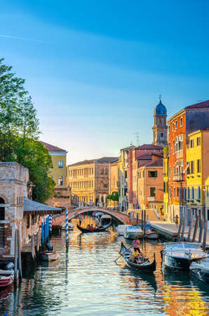 Venice, Italy, September 13, 2019: gondolier on gondola with tourists people sailing in narrow water canal between old colorful buildings and stone bridge in historical city center, Veneto Regionのeditorial素材