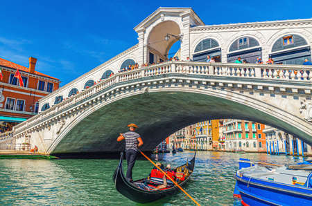 Venice, Italy, September 13, 2019: Rialto Bridge across Grand Canal waterway, Venetian architecture colorful buildings, gondolas boats sailing Canal Grande, blue sky in sunny day. Veneto Regionのeditorial素材